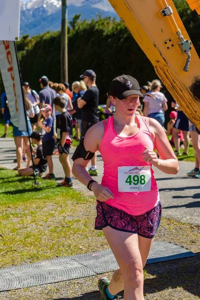 A woman in a pink tank top and shorts is running in a race.