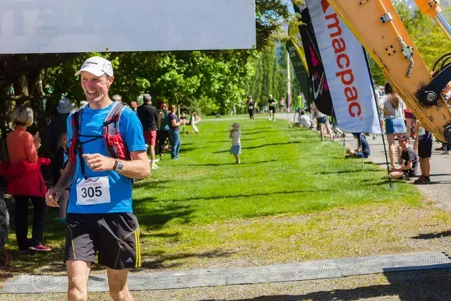 A man wearing a blue shirt with the number 305 on it is running in a park.