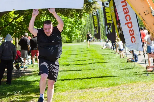 A man is carrying a sign over his head in a park.