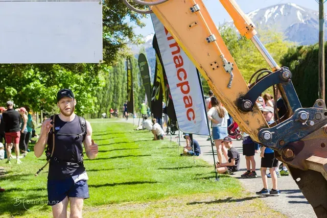 A man is standing in front of a large excavator.