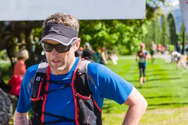 A man wearing sunglasses and a hat is standing in a field.