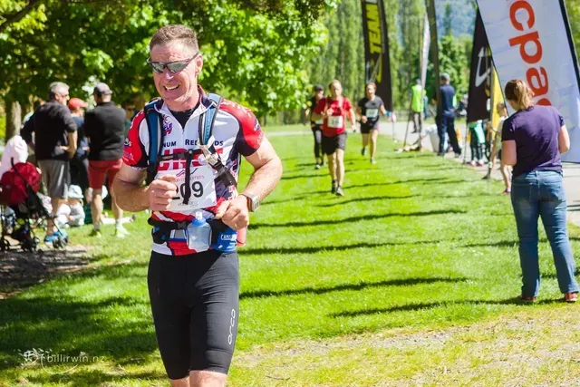 A man with the number 49 on his shirt is running in a park.