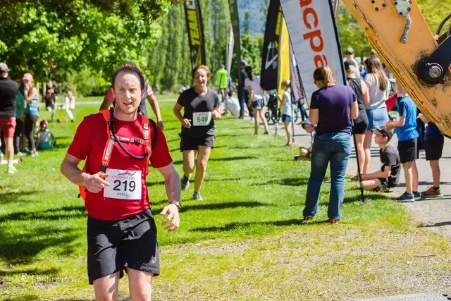 A man in a red shirt is running in a park.