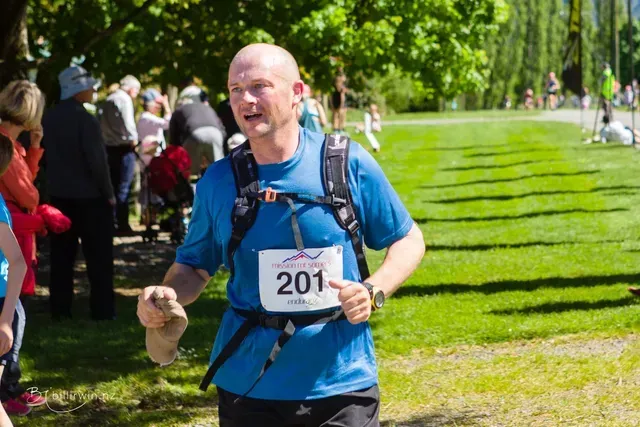 A man is running in a park with a number 201 on his shirt.