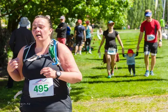 A woman is running in a park while holding a baby.
