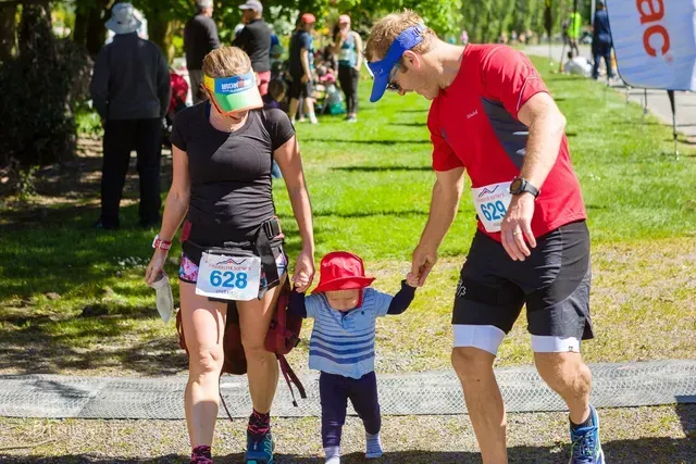 A man and woman are holding a child 's hand while running a race.