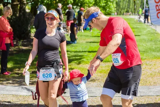 A man and a woman are holding a child 's hand while running a race.