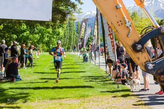A man is running in a park next to a large excavator.