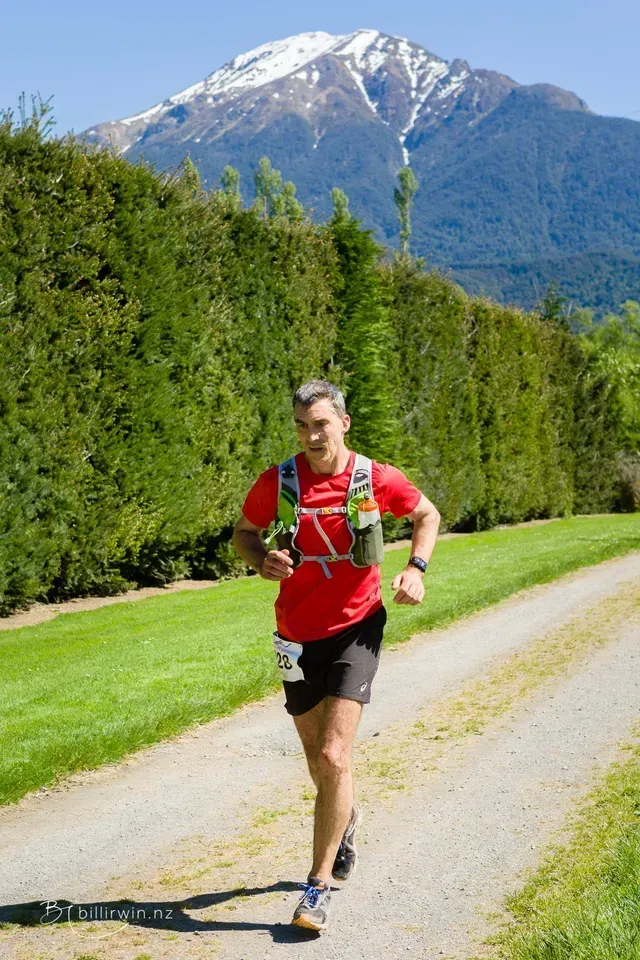 A man is running down a path with a mountain in the background.