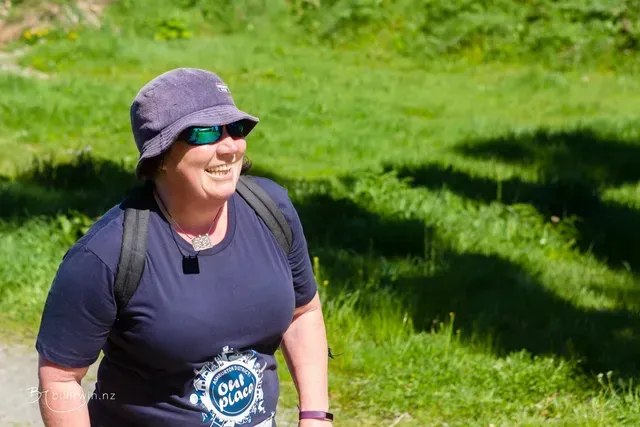 A woman wearing a hat and sunglasses is walking down a path.