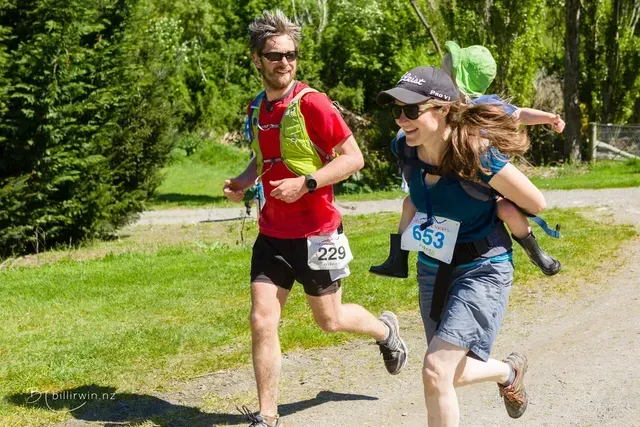 A man and a woman are running with a child on their shoulders.