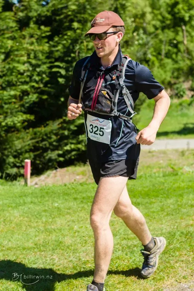 A man is running in a race on a grassy field.