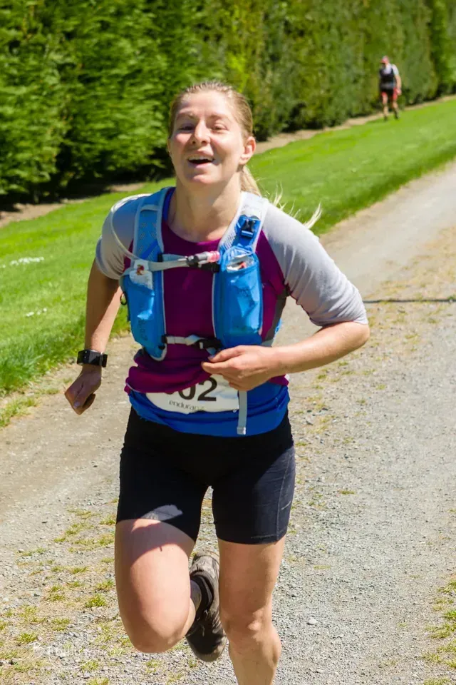 A woman is running a race on a dirt road.