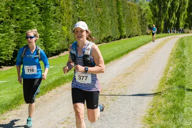 Two women are running down a dirt road.