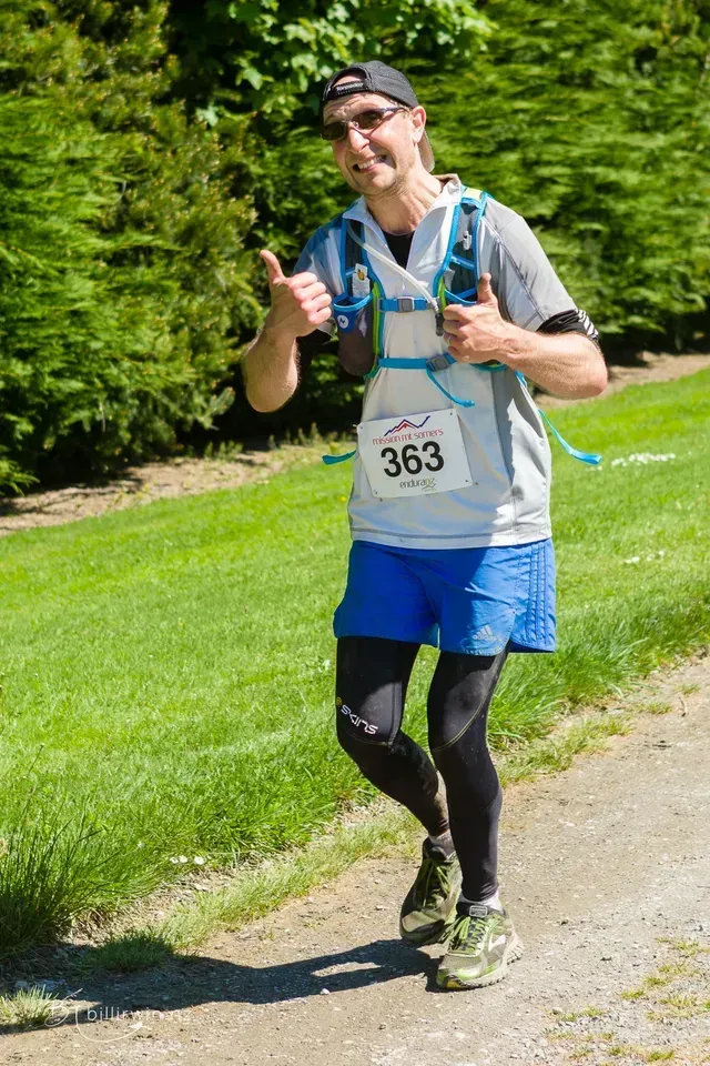 A man is running down a path and giving a thumbs up.