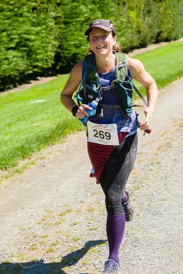 A woman is running a race on a dirt road.
