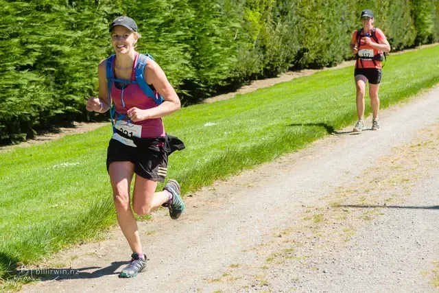 Two women are running down a dirt road.
