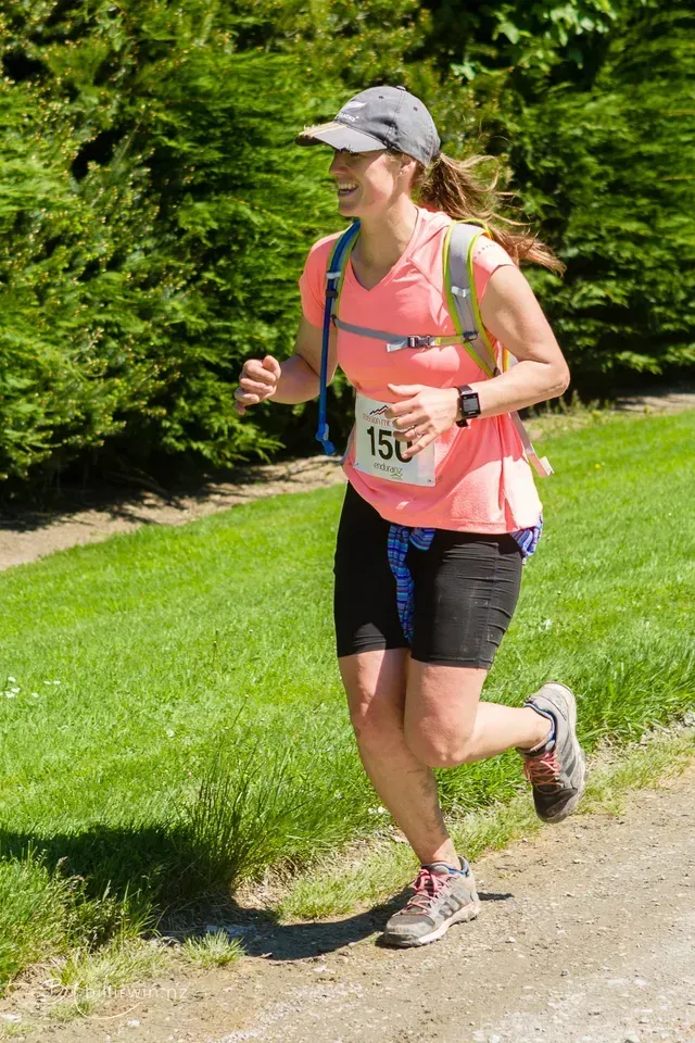 A woman is running a marathon on a dirt road.