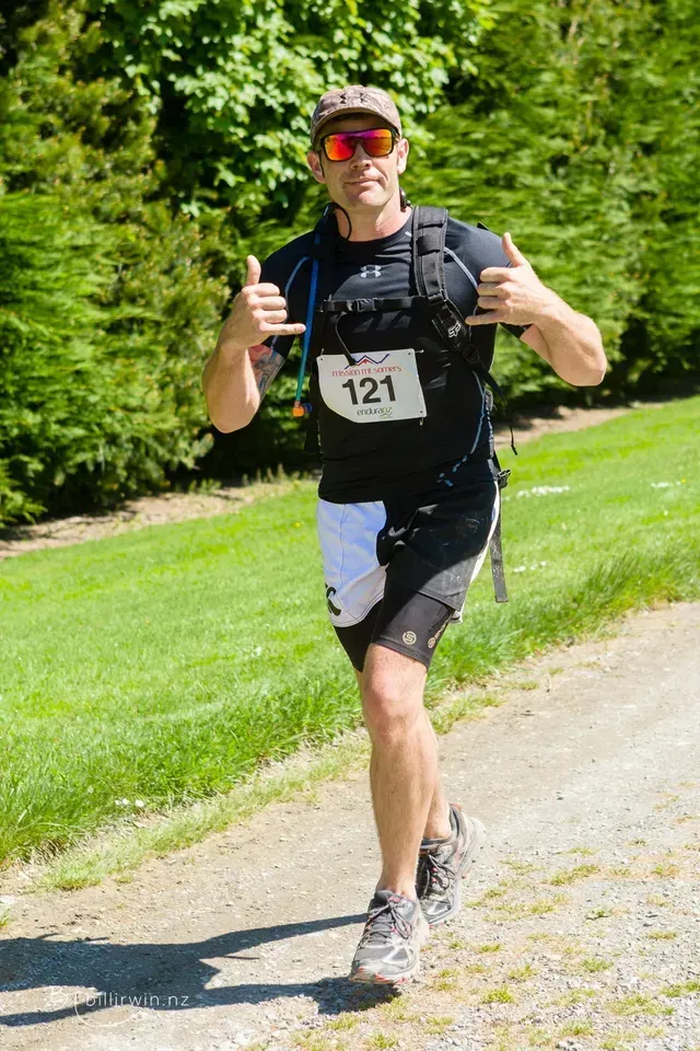 A man is running down a path and giving a thumbs up.
