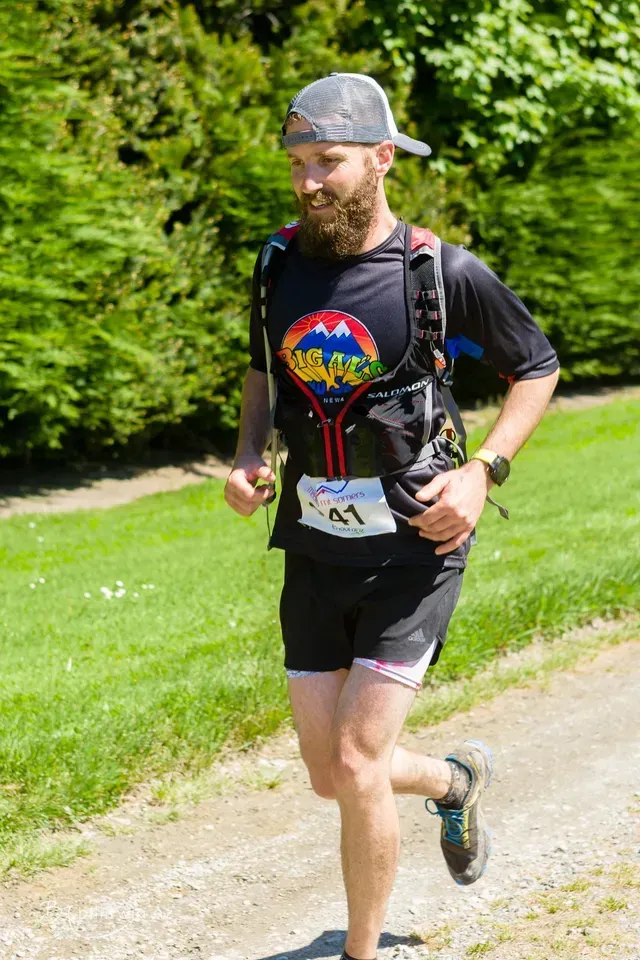 A man with a beard is running down a dirt road.