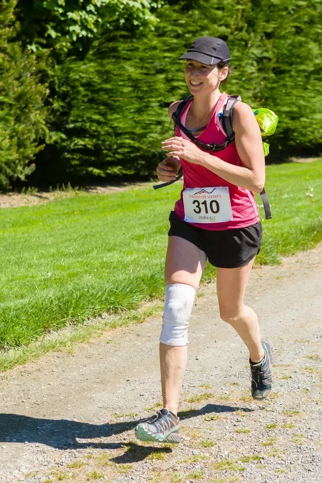 A woman is running in a race with the number 310 on her shirt.