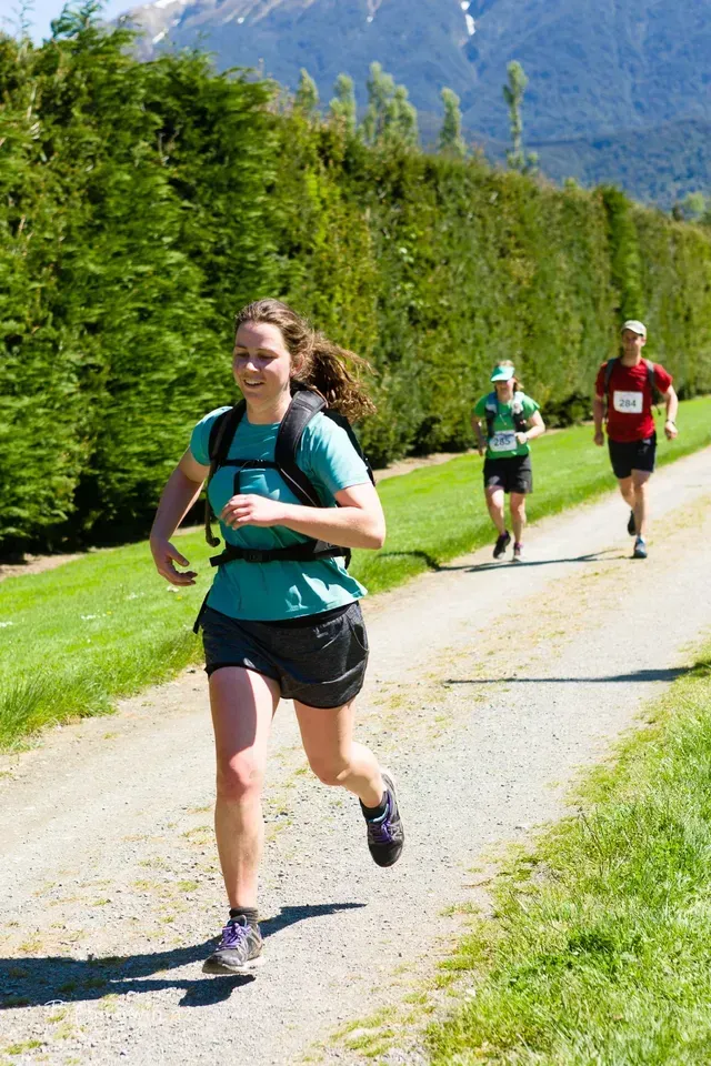 A group of people are running down a dirt road.