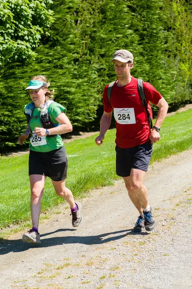 A man and a woman are running on a dirt road.