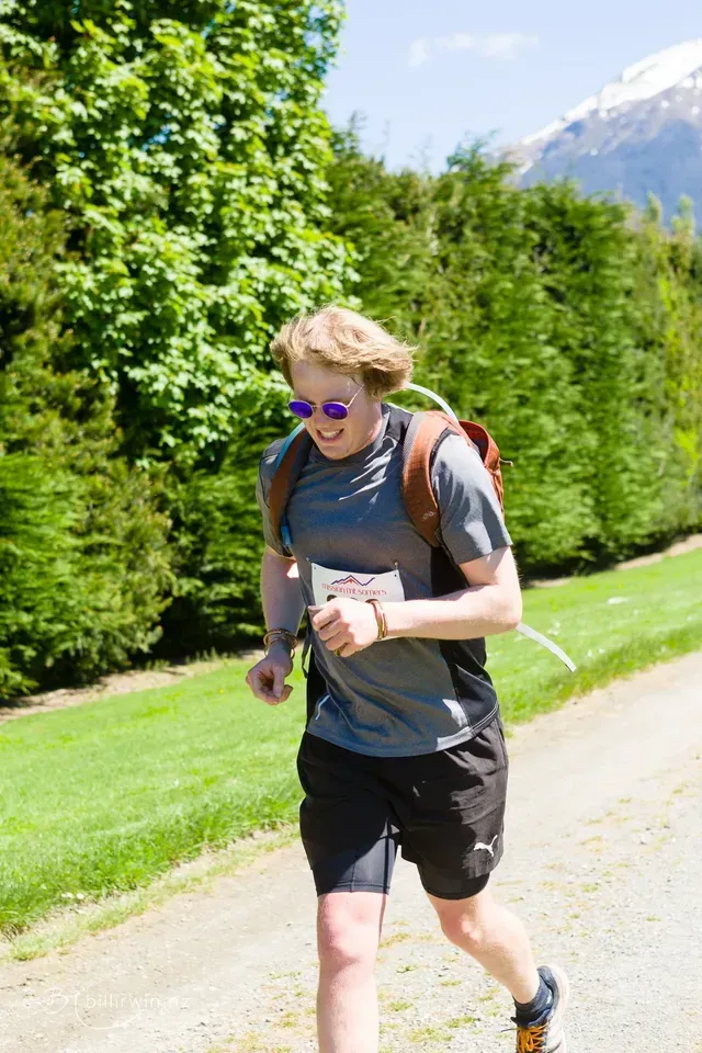 A man with a backpack is running down a path.
