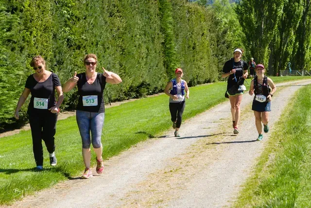 A group of women are running down a dirt road.