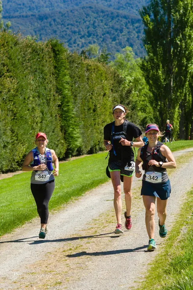A group of women are running down a dirt road.