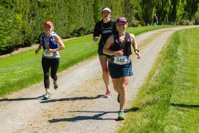 A group of women are running down a dirt road.