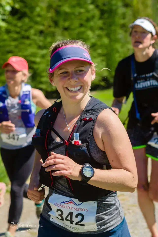 A woman is smiling while running in a race.