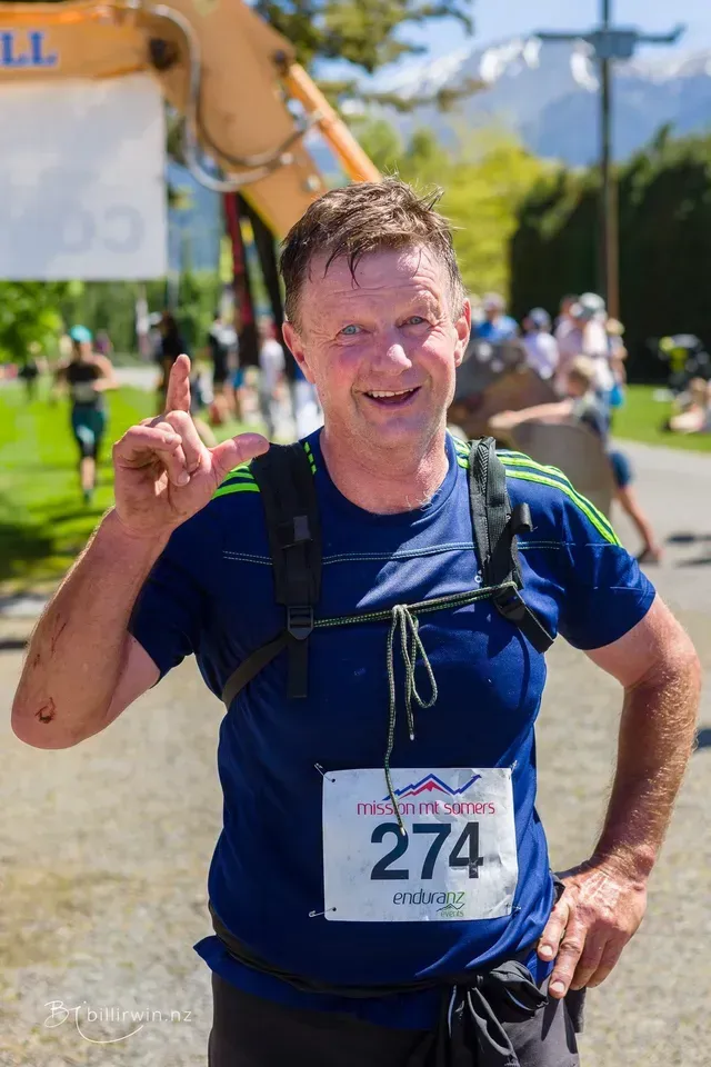 A man wearing a blue shirt with the number 274 on it is giving a peace sign.