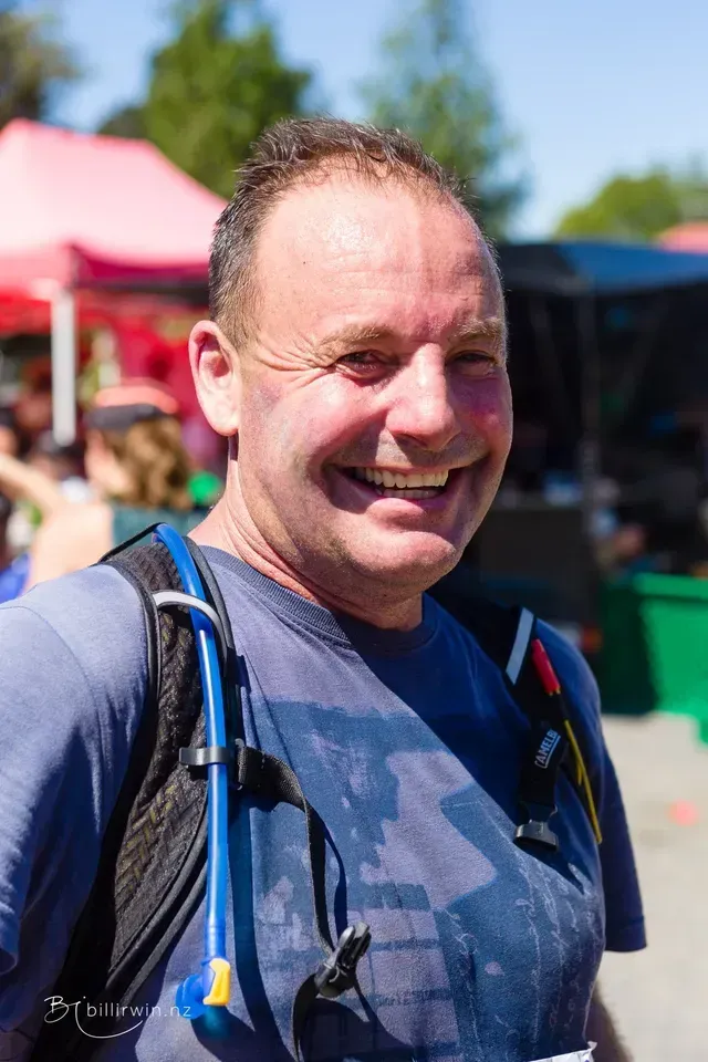 A man wearing a backpack is smiling for the camera