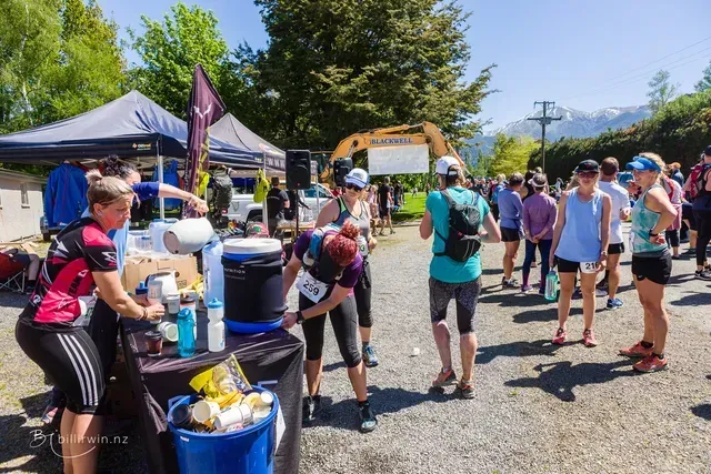 A group of people are standing around a table in a parking lot.