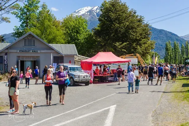 A group of people are walking down a street in front of a building.