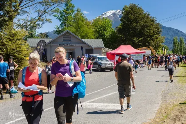 A group of people are walking down a street with mountains in the background.