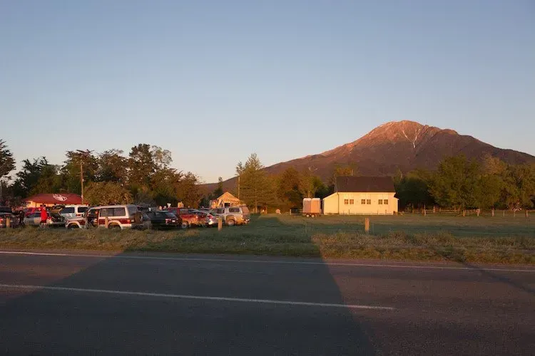 A parking lot with cars parked in front of a mountain.