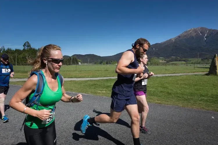A group of people are running on a road with mountains in the background.