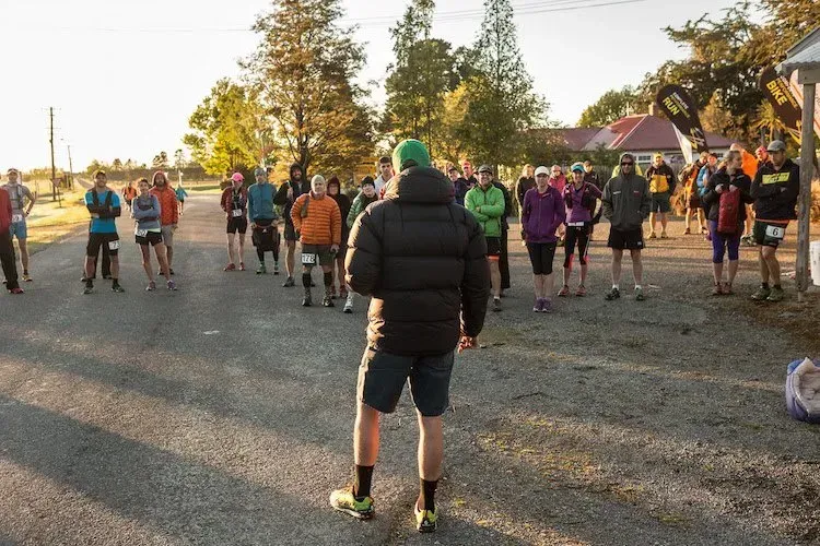 A man in a black jacket is standing in front of a group of people