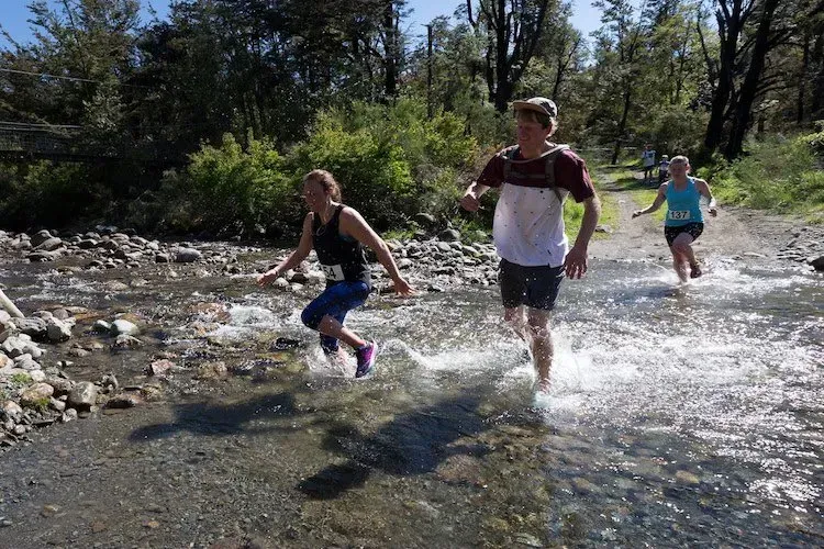A group of people are running through a river.