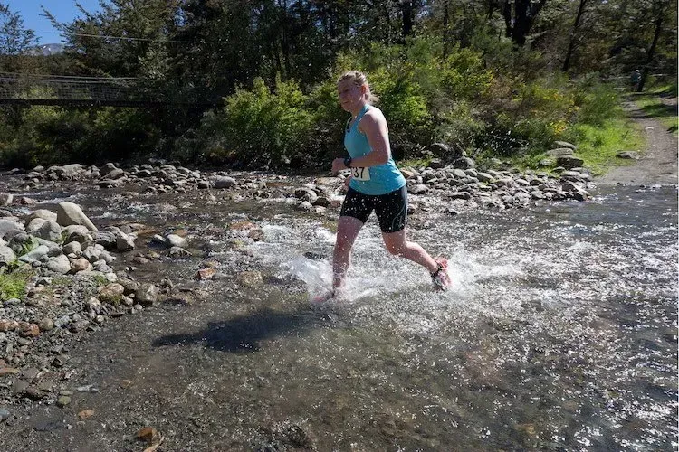 A woman is running through a stream of water.