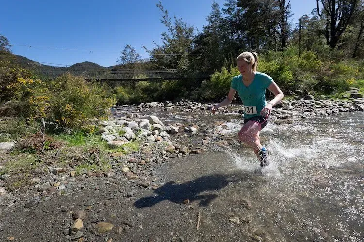 A woman is running through a stream of water.