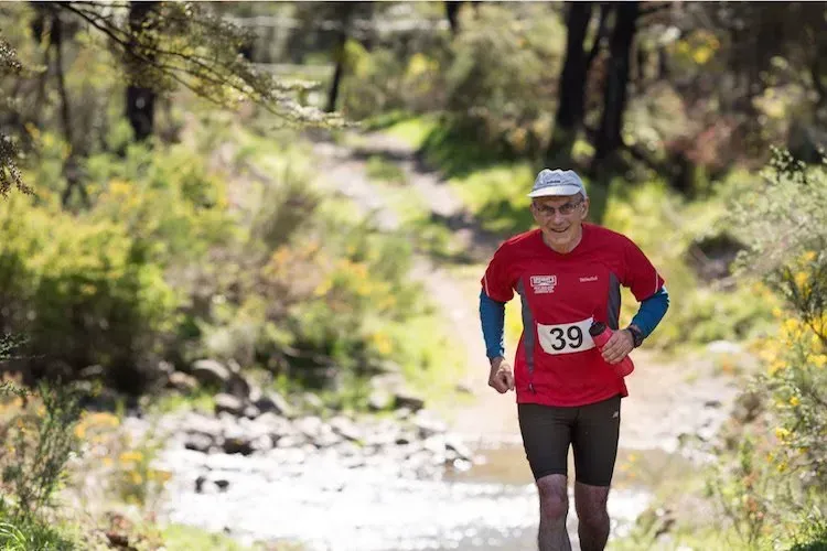 A man in a red shirt with the number 39 on it is running on a trail.