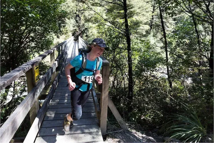 A person wearing a number 119 shirt is walking across a wooden bridge