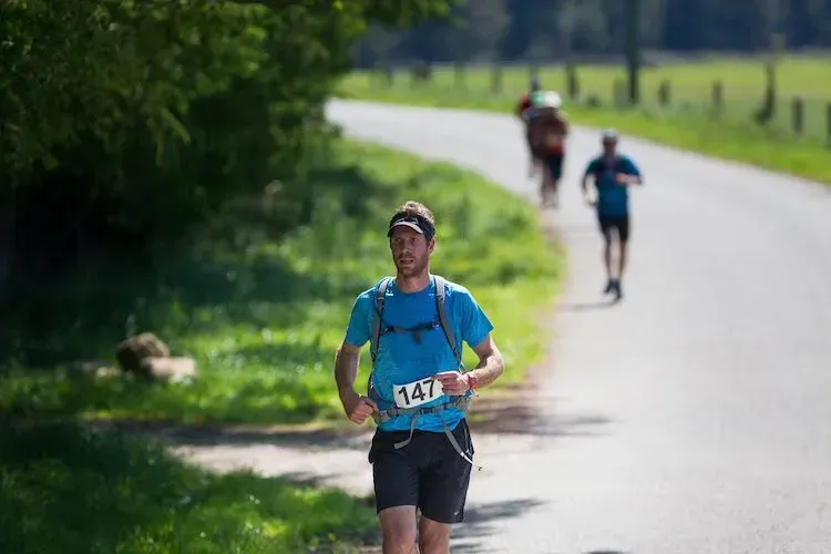 A man in a blue shirt is running down a road.