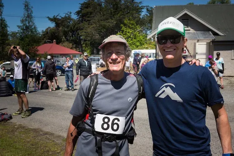 Two men are posing for a picture and one has the number 86 on his shirt