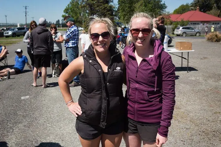 Two women are posing for a picture in a parking lot