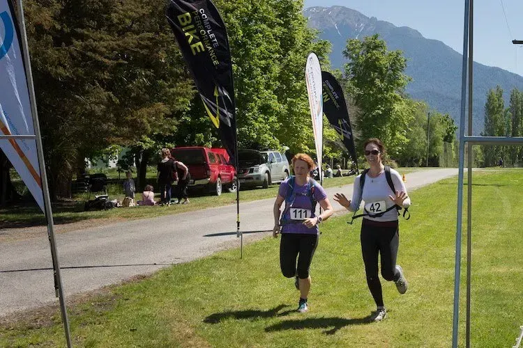 Two women are running in a park with mountains in the background.