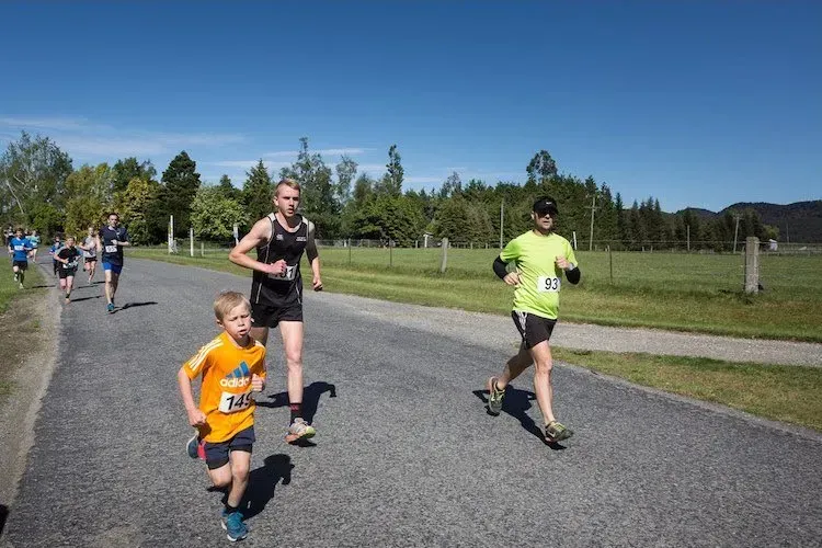 A group of people are running down a road.